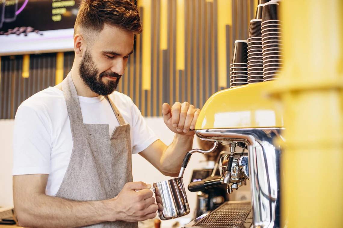 A barista whips milk in a coffee machine
