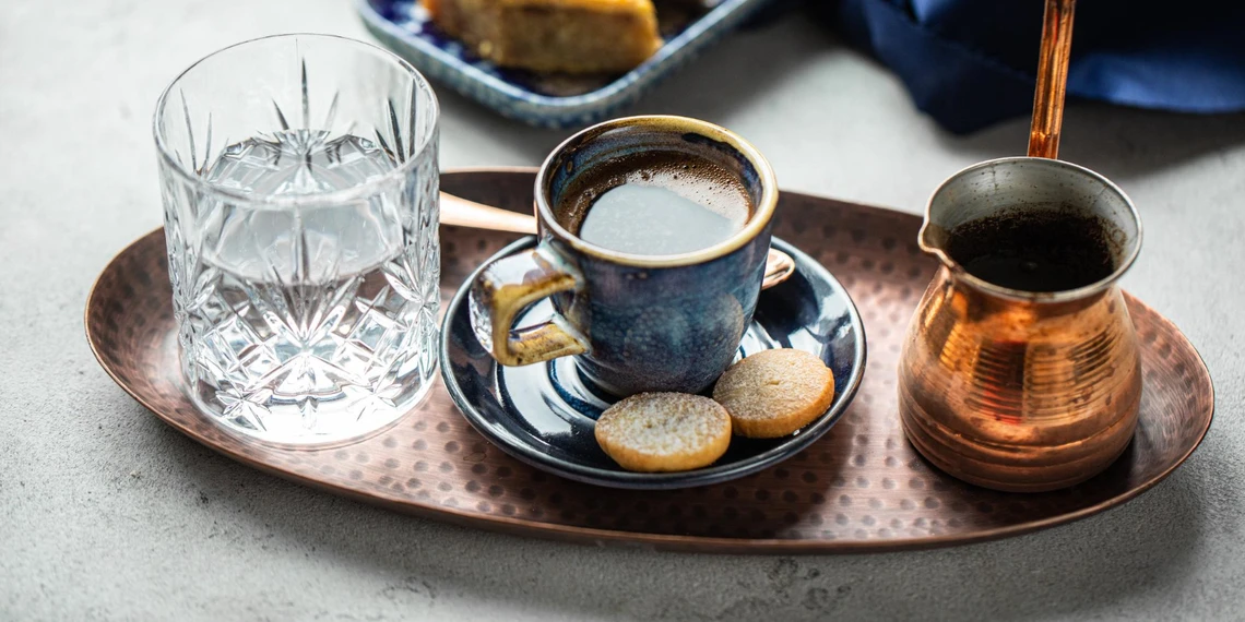 Pouring cold filtered water into ibrik with coffee grounds