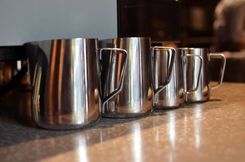 Different sizes of stainless steel milk pitchers for coffee preparation